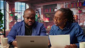 Black people both working from home at their designated office, using online tools on computer for tasks management. Completing operations efficiently from their comfortable house. Camera A. video