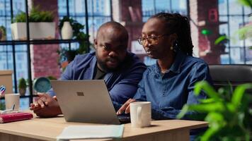 African american life partners working remotely in their cozy loft, planning development strategies and discussing project ideas while using a laptop to track progress. Cooperation. Camera B. video