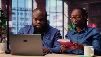 Woman completing spreadsheets on notebook, entering numerical data into cells, calculating totals. African american couple analyzing online information for an accounting task. Camera B. video