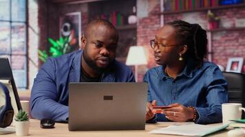 Young people using a card to check the financial balance before buying or paying something, e commerce from the home office. African american couple doing web transactions. Camera B. video