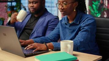 Young couple at desk reading research papers and multitasking with laptop at home office, diving into professional or personal topics of improvement. Self employed people review analysis. Camera A. video