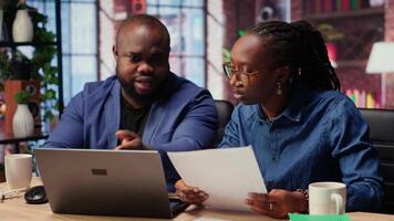 Black people both working from home at their designated office, using online tools on computer for tasks management. Completing operations efficiently from their comfortable house. Camera B. video