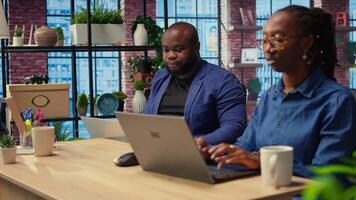 African american couple work on a management project together, using a laptop to research business trends and manage an online brand. Successful remote career development as a team. Camera A. video