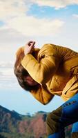 Vertical Clumsy traveler loses balance on a steep mountain peak as powerful winds knock him off course, falling and being unequipped in expedition. Unprepared hiker for the cold weather. Camera B. video