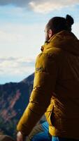 Vertical Hiker takes a moment to admire the panoramic view of mountains, looking into the distance and sightseeing. Fresh air, scenic background and peaceful surroundings for an explorer. Camera A. video