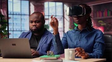 Black people integrate VR and AI into their daily job routine where the man engages in immersive 3D experience. Young focused woman reviews the animation on headset within the metaverse. Camera B. video