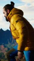 Vertical Determined climber pauses to admire the scenic view with mountains and a vast sky create a breathtaking backdrop. Man hiking for exploration and adventure in the nature. Camera A. video