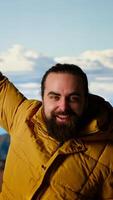 Vertical Triumphant hiker stands at the mountain peak with his arms raised in victory, celebrating success and personal achievement of climbing another mountain. Breathtaking panoramic view. Camera B. video