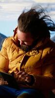 Vertical Traveler tries to stay connected in the wilderness but struggles with weak signals, dangerous wind at the top of the mountain. Hiker setting up his tent on a rocky windy peak. Camera B. video