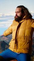 Vertical Adventure seeker stands at the peak with the satisfaction of a successful climb, being proud and enjoying the crisp wind at the mountain top. Loving the freedom and nature. Camera B. video