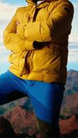 Vertical Hiker stands victorious on a mountain peak with arms raised in triumph, celebrating his personal achievement with a successful climb. Scenic view and endless sky for freedom. Camera A. video