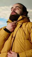 Vertical Mountain hiker zipping his jacket after climbing to the top with a vast landscape of peaks and sky, embracing the adventure of trekking through the wilderness. Outdoor exploration. Camera B. video