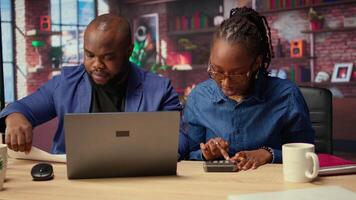 African American couple discusses mortgage and insurance payments at home, using calculator to do their household budgeting and money management. Ensuring a secure financial future. Camera A. video