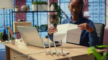African american woman restarting her wireless router and checking network settings to resolve an internet error disrupting her daily tasks. Frustration due to signal loss. Camera A. video