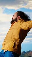 Vertical Happy adventurer embraces the thrill of standing at the top of the mountain, feeling the power of accomplishment. Awe inspiring mountain range with peaceful sky and vast wilderness. Camera B. video