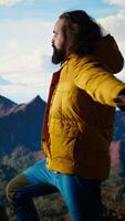 vertical aventuras buscador soportes a el pico con el satisfacción de un exitoso trepar, siendo orgulloso y disfrutando el crujiente viento a el montaña cima. amoroso el libertad y naturaleza. cámara una. video
