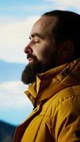 Vertical Determined explorer gazes at the endless sky and towering peaks, reflecting on extreme hiking activity and conquering fears. Enjoys breathtaking mountain view, nature lover. Camera B. video
