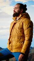 Vertical Peaceful pleased traveler feeling happy climbing the mountain, enjoying mindfulness and determination. Young man being passionate about the wilderness and the scenic view. Camera B. video