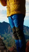 Vertical Pleased calm nature lover meditating on top of the mountain range, doing meditation poses and taking deep breaths for wellbeing and mental clarity. Peaceful zen hiker enjoys climbing. Camera A. video