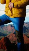 Vertical Mountain hiker zipping his jacket after climbing to the top with a vast landscape of peaks and sky, embracing the adventure of trekking through the wilderness. Outdoor exploration. Camera A. video