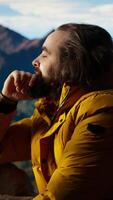 Vertical Male active trekker admiring the beautiful mountain range valley but dealing with cold winds, struggling with dangerous windy weather in his campsite. Wanderlust in nature. Camera A. video