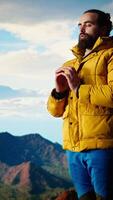Vertical Young explorer reaching the mountain peak and meditating at the top, doing a zen meditation with calm and mindfulness. Happy content hiker loving nature for self care. Camera A. video