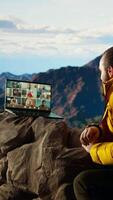 Vertical Entrepreneur uses high speed internet connection on mountain top, enjoying the call with a scenic landscape. Young hiker having an internet dependency and being workaholic. Camera A. video