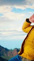 Vertical Joyful hiker triumphant at the mountain top dancing and cheering, soaks in the peaceful atmosphere and fresh air. Enjoying the scenic background of towering peaks and clouds. Camera A. video