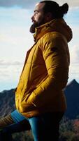 Vertical Explorer stands on a mountain peak taking in the fresh air and panoramic scenery. Hiker admires the stunning landscape of rugged peaks and vast sky, adventure and sightseeing. Camera B. video