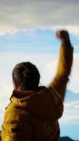 Vertical Hiker dressed in warm outdoor gear celebrates reaching the top of a mountain, stunning view and sense of satisfaction embodies the thrill of adventure and personal strength. Camera B. video