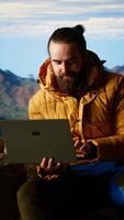 Vertical Nature lover workaholic always connected to the internet and scrolling on laptop, enjoying strong signal on a mountain top with a breathtaking landscape. Uninterrupted work. Camera B. video