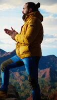 Vertical Traveler stands alone in the high altitude wilderness admiring the breathtaking scenery, enjoying fresh air and stunning mountain top landscape. Peaceful atmosphere inspire mindfulness. Camera A. video
