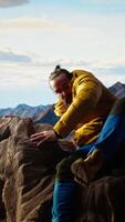 Vertical Determined climber standing at the summit enjoys peaceful moment of success. Vast sky, mountain range and fresh air highlighting the essence of freedom, wellness and exploration. Camera A. video