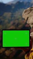 Vertical Happy adventurer standing at the rocky top next to copy space display, feeling the power of accomplishment. Examines the mountain range, peaceful sky and vast wilderness. Camera B. video
