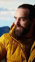 Vertical Satisfied adventurer celebrates personal success on a mountain peak, taking a breath and enjoying the scenic view at the top. Motivation for adventure and outdoor exploration. Camera A. video