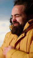 Vertical Young traveler struggling with cold winds on top of the mountain, feeling proud of his trekking activity. Adventure seeker with ambition successfully climbing the mountain range. Camera B. video