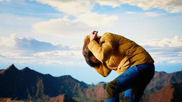 Clumsy traveler loses balance on a steep mountain peak as powerful winds knock him off course, falling and being unequipped in expedition. Unprepared hiker for the cold weather. Camera B. video