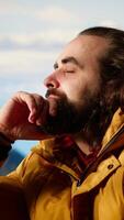 Vertical Male active trekker admiring the beautiful mountain range valley but dealing with cold winds, struggling with dangerous windy weather in his campsite. Wanderlust in nature. Camera B. video