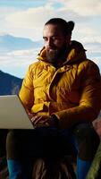 Vertical Hiker with a technology obsession and strong signal working in nature, climbing the top of the mountain and connecting to work platform. Workaholic person enjoying internet everywhere. Camera A. video