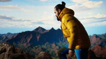 Determined climber pauses to admire the scenic view with mountains and a vast sky create a breathtaking backdrop. Man hiking for exploration and adventure in the nature. Camera A. video