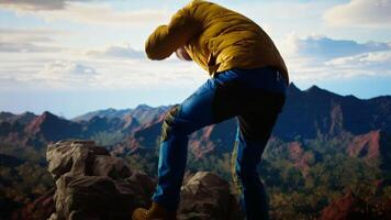 Clumsy traveler loses balance on a steep mountain peak as powerful winds knock him off course, falling and being unequipped in expedition. Unprepared hiker for the cold weather. Camera A. video