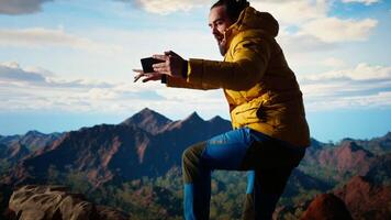 Reckless adventurer losing balance to take a picture and dropping phone off a cliff, falling down from a high altitude mountain range. Foolish hiker tries to take photos of a landscape. Camera A. video