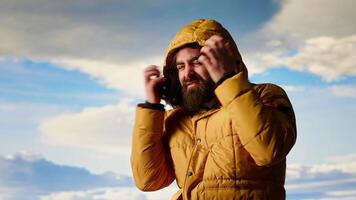 Adventure seeker climbing the mountain with extreme windy weather, feeling happy with his achievement. Young hiker feeling the cold wind on the hill top, scenic background. Camera B. video