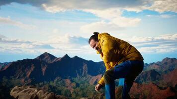 Reckless unprepared hiker stumbles near the edge of a high altitude cliff, caught off guard by strong winds. Unequipped for the extreme conditions, losing balance on mountain top. Camera A. video