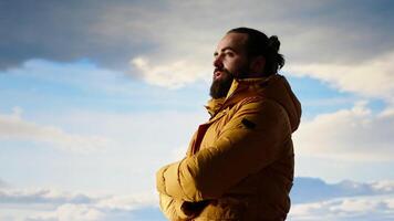 Hiker stands victorious on a mountain peak with arms raised in triumph, celebrating his personal achievement with a successful climb. Scenic view and endless sky for freedom. Camera B. video