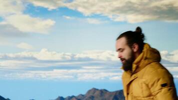 Alone traveler stands on a mountain summit soaking in the stunning view of peaks, clouds and endless sky, adventure seeker. Breathtaking scenery symbolizes determination. Camera B. video