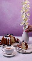 Woman arranging white orchids in vase on table with cake and cappuccino video