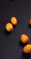 fresco kumquats queda para uma Preto superfície, criando uma visualmente atraente exibição com verde folhas video