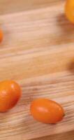 Kumquats falling and rolling on wooden table video