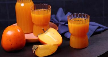 Fresh persimmon juice and whole fruit displayed on table video